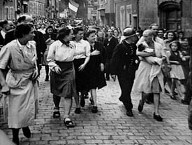 A Frenchwoman with her baby fathered by a German soldier, punished by having her head shaved after the liberation of the town, Chartres, August 18, 1944